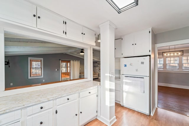 kitchen featuring light wood finished floors, white cabinets, lofted ceiling, freestanding refrigerator, and light countertops