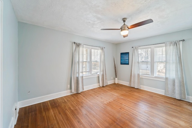 unfurnished room featuring light wood-style floors, baseboards, and a textured ceiling