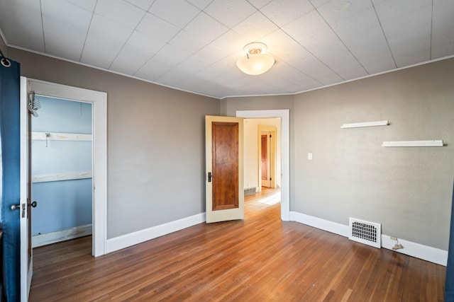 unfurnished bedroom with baseboards, a closet, visible vents, and wood finished floors