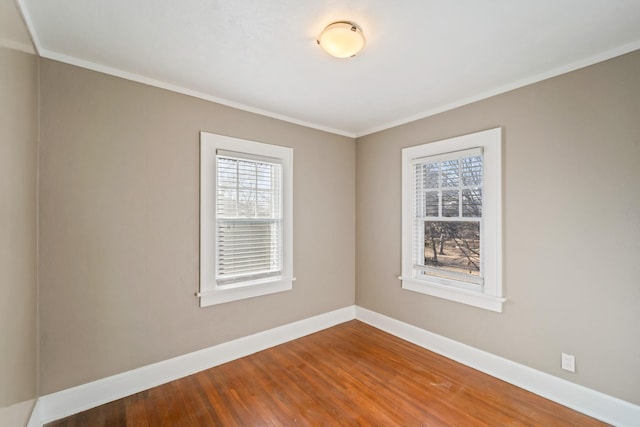 unfurnished room with crown molding, wood finished floors, a wealth of natural light, and baseboards