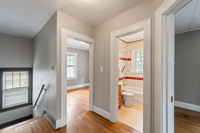 6015 Waterbury Cir, Des Moines, IA 50312 - hall featuring an upstairs landing, wood finished floors, plenty of natural light, and baseboards