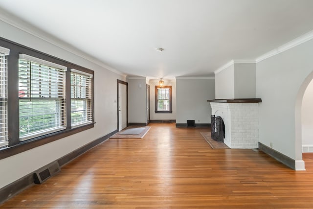 6015 Waterbury Cir, Des Moines, IA 50312 - unfurnished living room with light wood-style flooring, arched walkways, crown molding, a brick fireplace, and baseboards