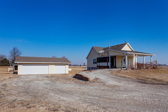 view of front of house with covered porch, a detached garage, and an outbuilding