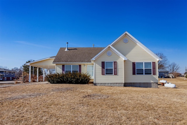 view of front of home with a shingled roof, a front yard, and a carport