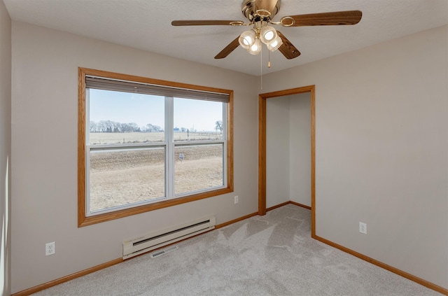 spare room with carpet floors, a baseboard radiator, baseboards, and ceiling fan