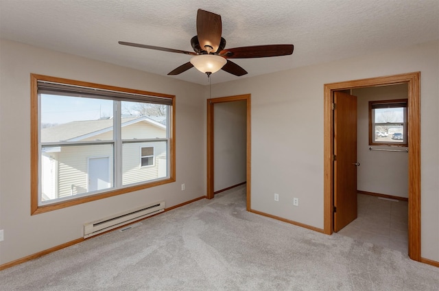 spare room featuring a baseboard heating unit, a healthy amount of sunlight, baseboards, and light colored carpet