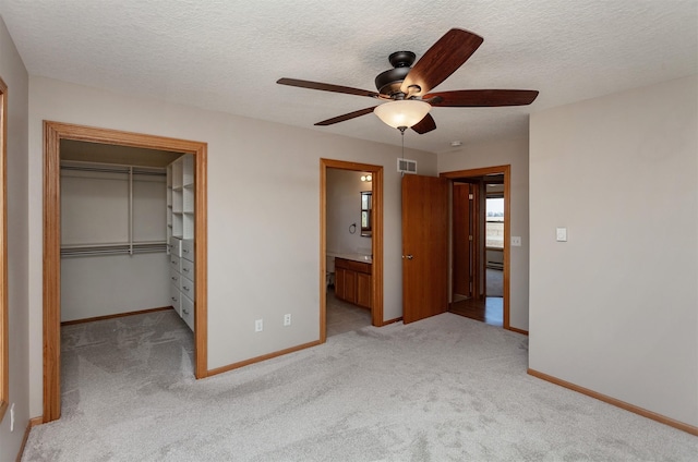 unfurnished bedroom with light carpet, baseboards, visible vents, and a walk in closet