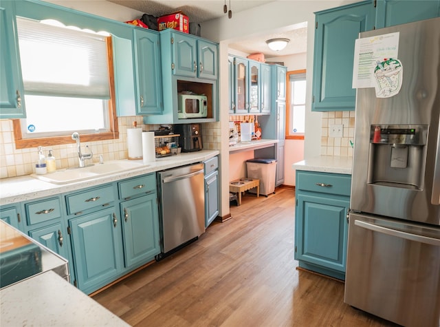 kitchen featuring stainless steel appliances, light wood-style floors, a sink, and plenty of natural light