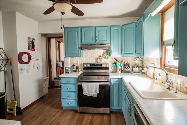 kitchen featuring appliances with stainless steel finishes, dark wood-style flooring, light countertops, under cabinet range hood, and a sink