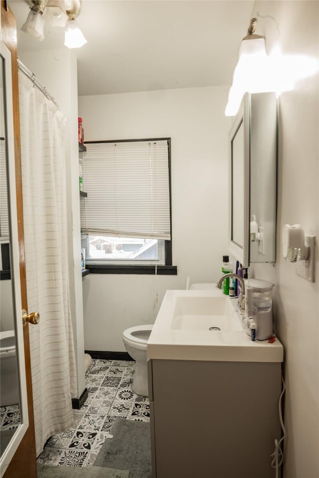 bathroom with toilet, curtained shower, tile patterned flooring, and vanity