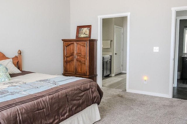 bedroom with light colored carpet, baseboards, and ensuite bathroom