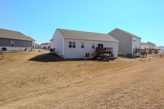 rear view of house with stairway, a deck, and a lawn