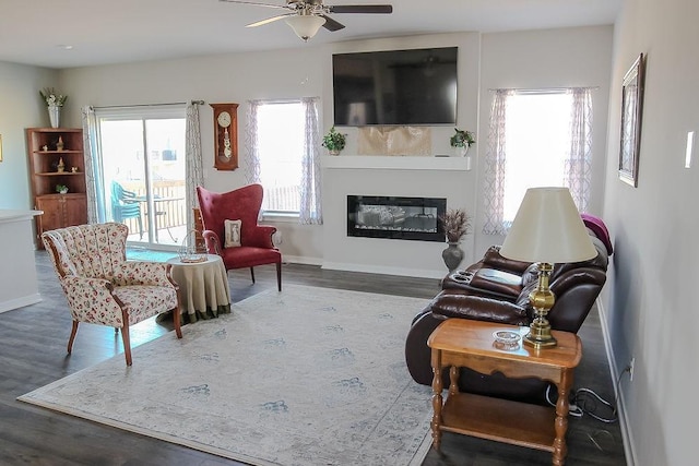 sitting room with a glass covered fireplace, wood finished floors, and baseboards