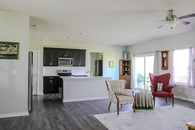 interior space with dark cabinets, stainless steel appliances, baseboards, decorative backsplash, and dark wood finished floors