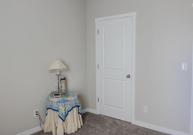 interior space with dark colored carpet and baseboards