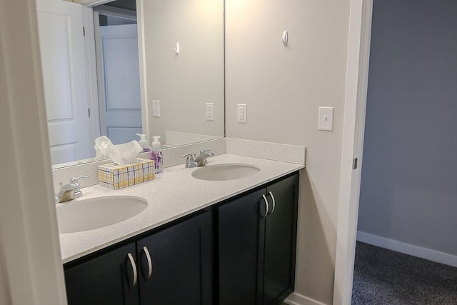 full bath featuring double vanity, baseboards, and a sink