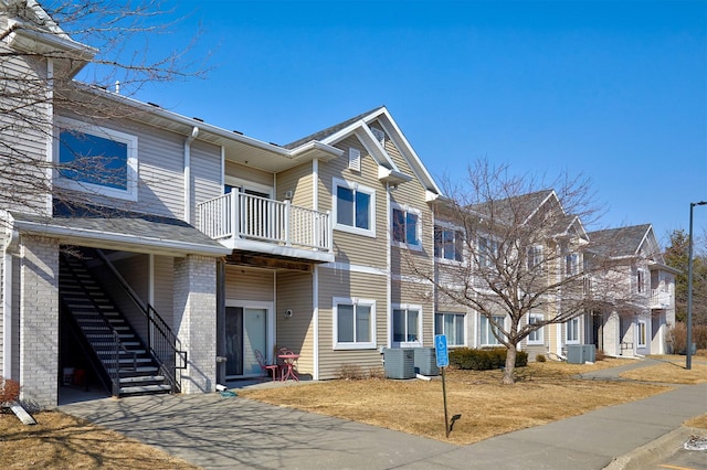 townhome / multi-family property with a residential view, brick siding, a balcony, and central AC unit