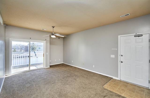 carpeted spare room featuring visible vents, ceiling fan, a textured ceiling, and baseboards