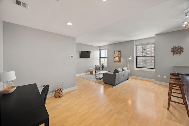 living area with recessed lighting, visible vents, baseboards, and wood finished floors