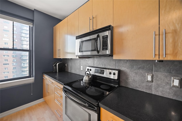 kitchen with dark countertops, tasteful backsplash, baseboards, and stainless steel appliances