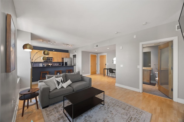 living area featuring light wood-type flooring, visible vents, and baseboards