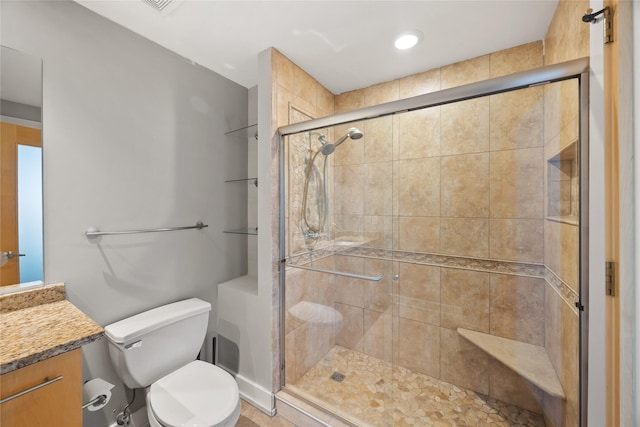 bathroom featuring a shower stall, toilet, and vanity