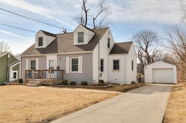 new england style home featuring brick siding, a detached garage, a shingled roof, concrete driveway, and an outdoor structure