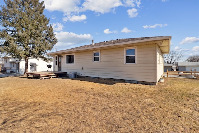 rear view of property featuring a lawn, cooling unit, a wooden deck, and fence