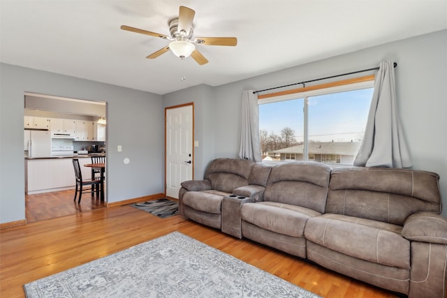 living room featuring light wood-style floors, baseboards, and a ceiling fan