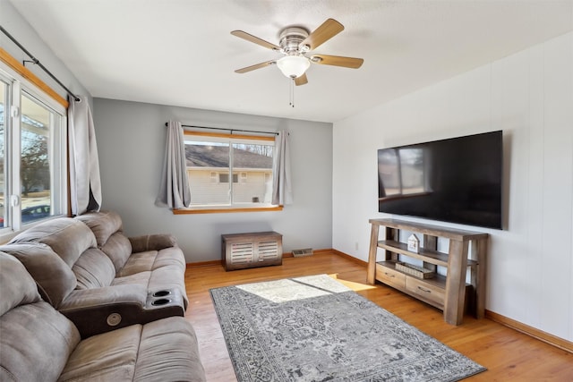 living room with ceiling fan, baseboards, and wood finished floors