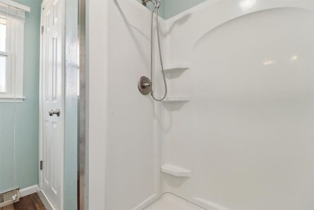 bathroom with a shower, visible vents, and wood finished floors