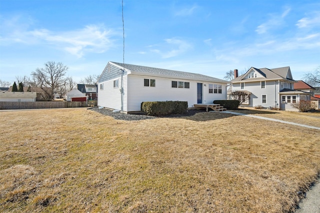 view of front of home with entry steps, a front yard, and fence