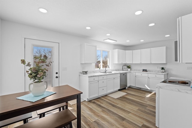 kitchen with recessed lighting, light wood-style flooring, white cabinets, and a sink