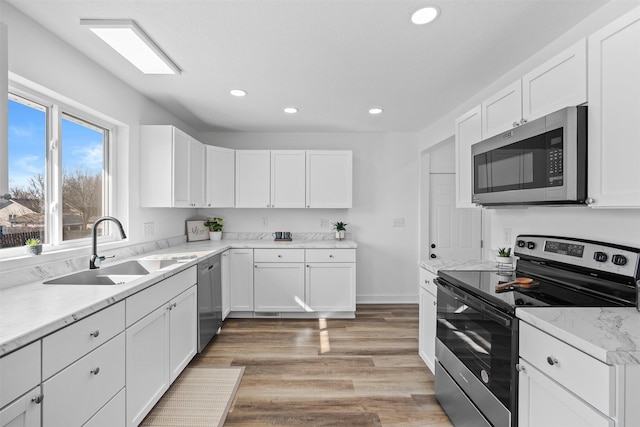 kitchen with recessed lighting, light wood-style flooring, stainless steel appliances, white cabinetry, and a sink