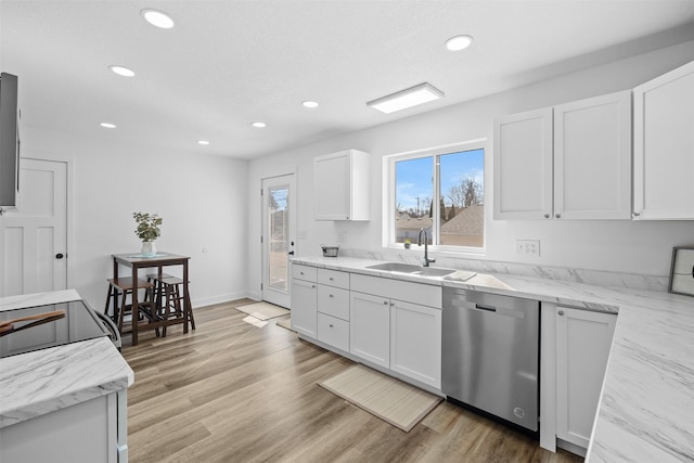 kitchen featuring light wood finished floors, dishwasher, light stone counters, white cabinetry, and a sink