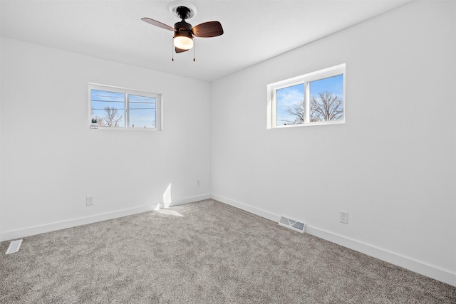 carpeted empty room featuring a wealth of natural light, visible vents, and baseboards