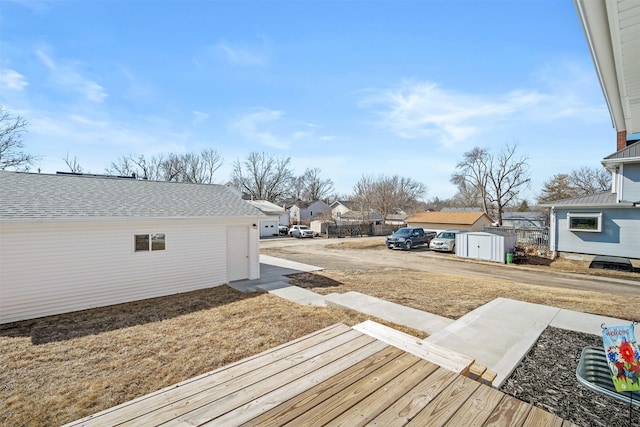 wooden terrace with an outbuilding, a residential view, a storage shed, and fence