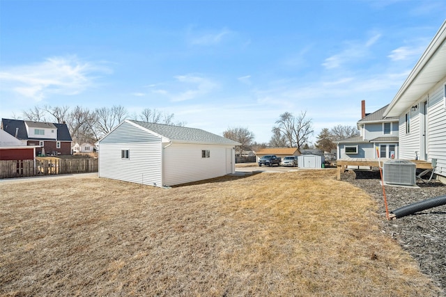 view of yard featuring central air condition unit, an outbuilding, a storage shed, and fence