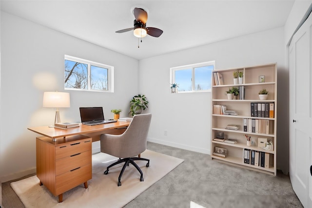 office area with ceiling fan, baseboards, and light carpet