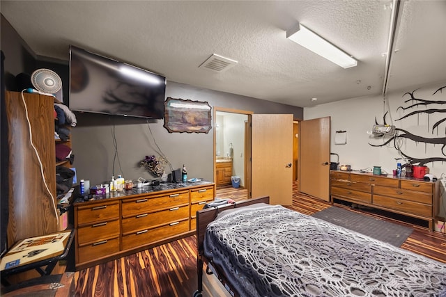 bedroom with visible vents, a textured ceiling, and wood finished floors