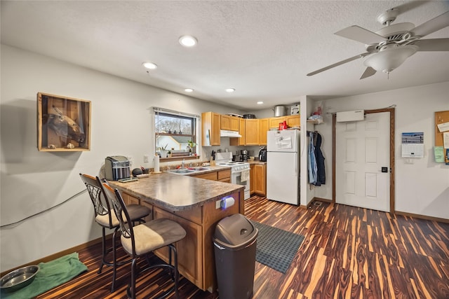 kitchen featuring a peninsula, white appliances, a textured ceiling, and dark wood-style flooring