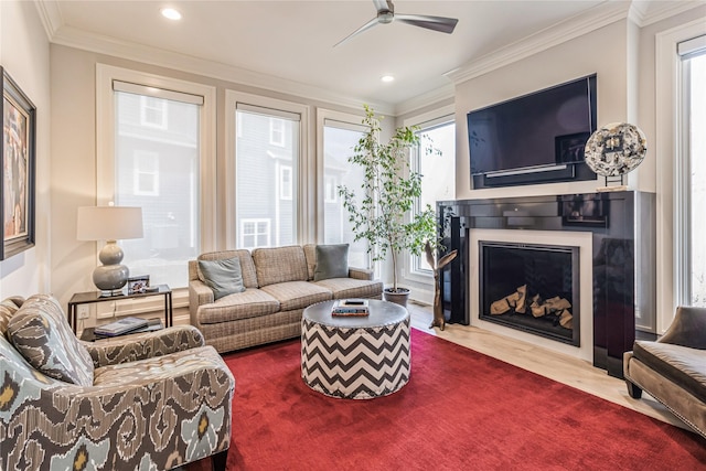 living room with a ceiling fan, a fireplace with flush hearth, wood finished floors, crown molding, and recessed lighting