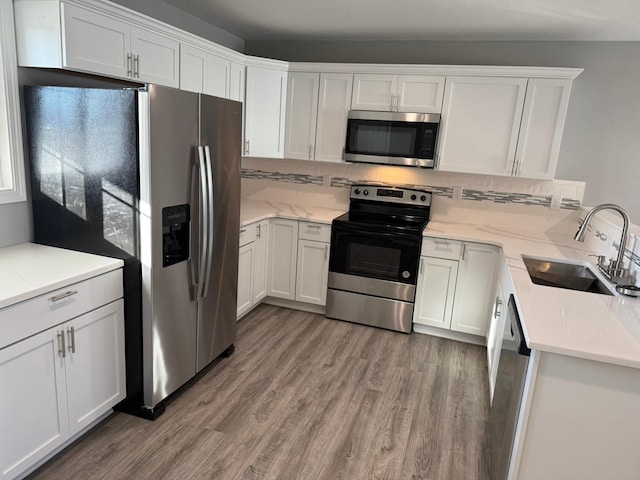 kitchen featuring light wood-type flooring, white cabinetry, appliances with stainless steel finishes, and a sink