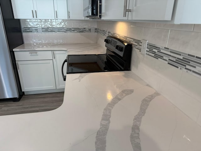 kitchen with light stone counters, appliances with stainless steel finishes, white cabinetry, and decorative backsplash