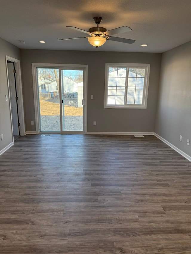 empty room with dark wood finished floors, a ceiling fan, and baseboards