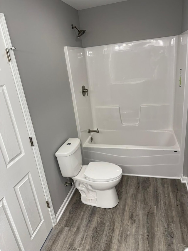 full bath with  shower combination, wood finished floors, toilet, and baseboards