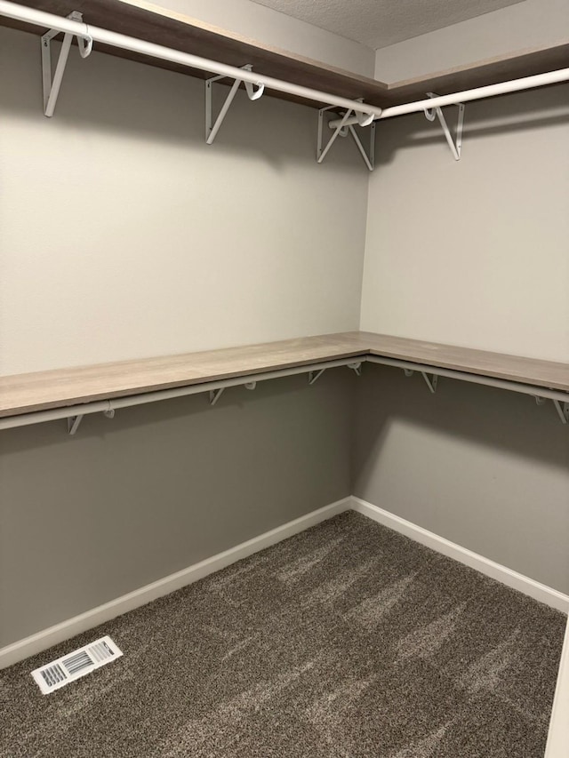 spacious closet featuring dark carpet and visible vents