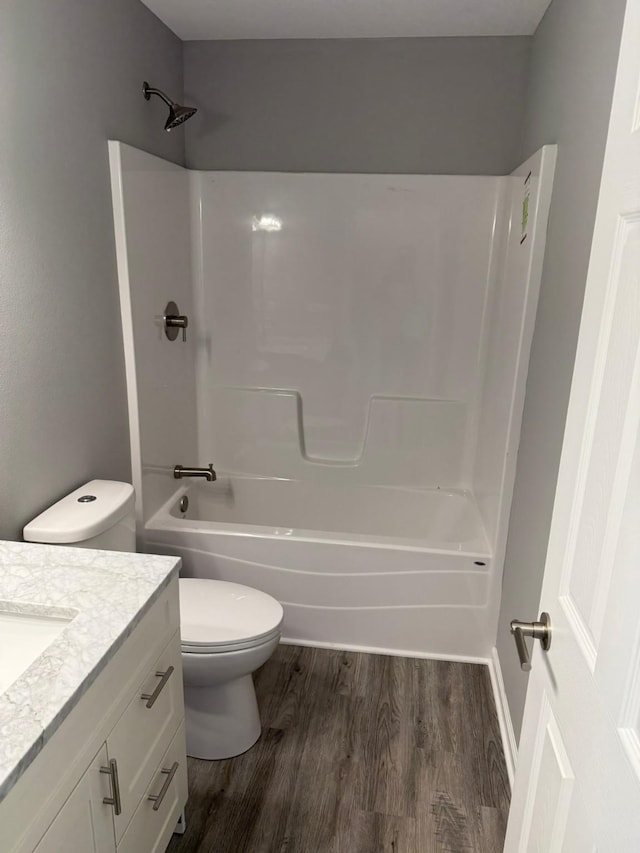 bathroom featuring toilet, shower / tub combination, wood finished floors, and vanity