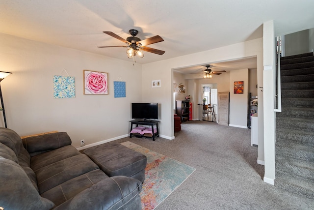 carpeted living area featuring a ceiling fan, baseboards, and stairs