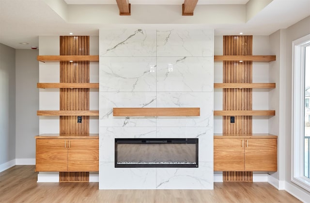 unfurnished living room with light wood-style floors, a premium fireplace, and baseboards